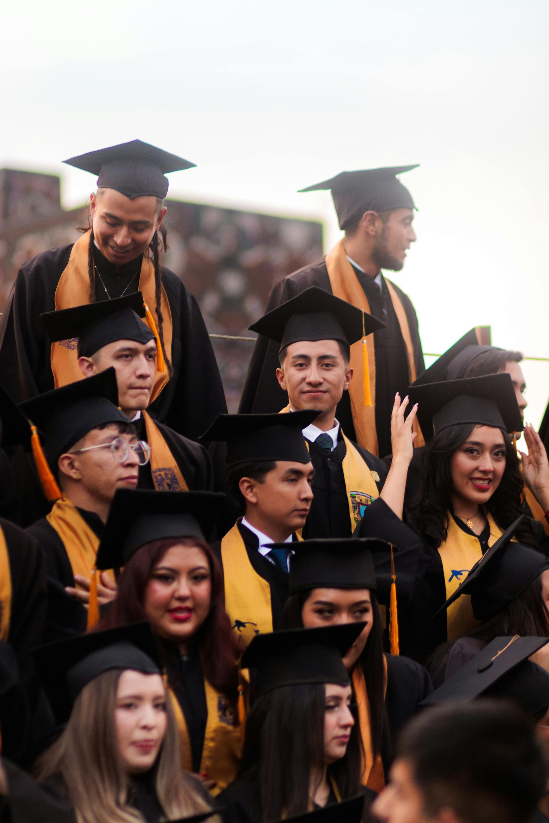 Graduates in black caps and gowns smiling together at a ceremony