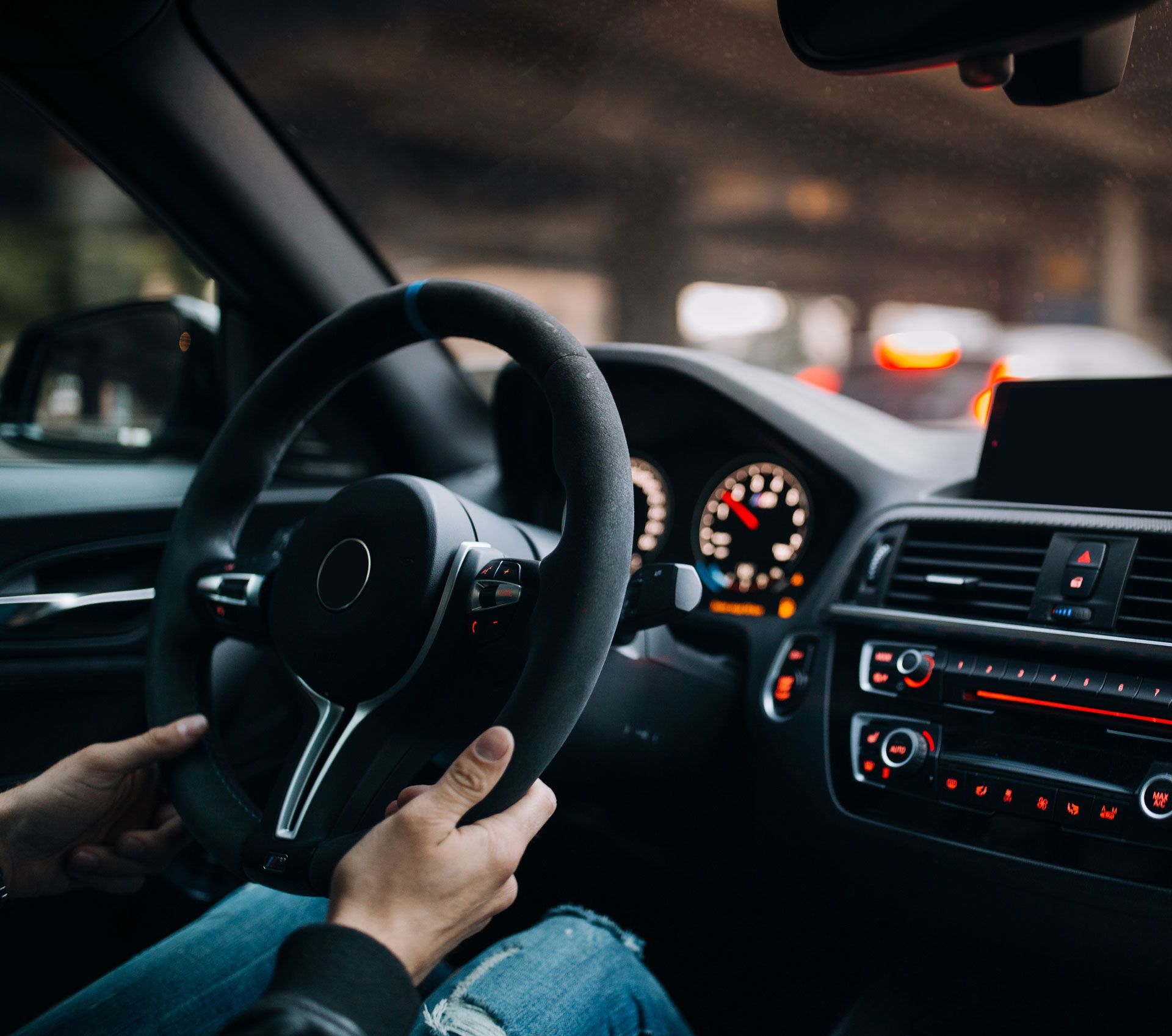 A person is sitting in a car holding the steering wheel