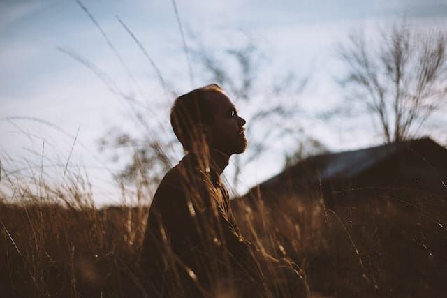 A man is sitting in a field of tall grass.