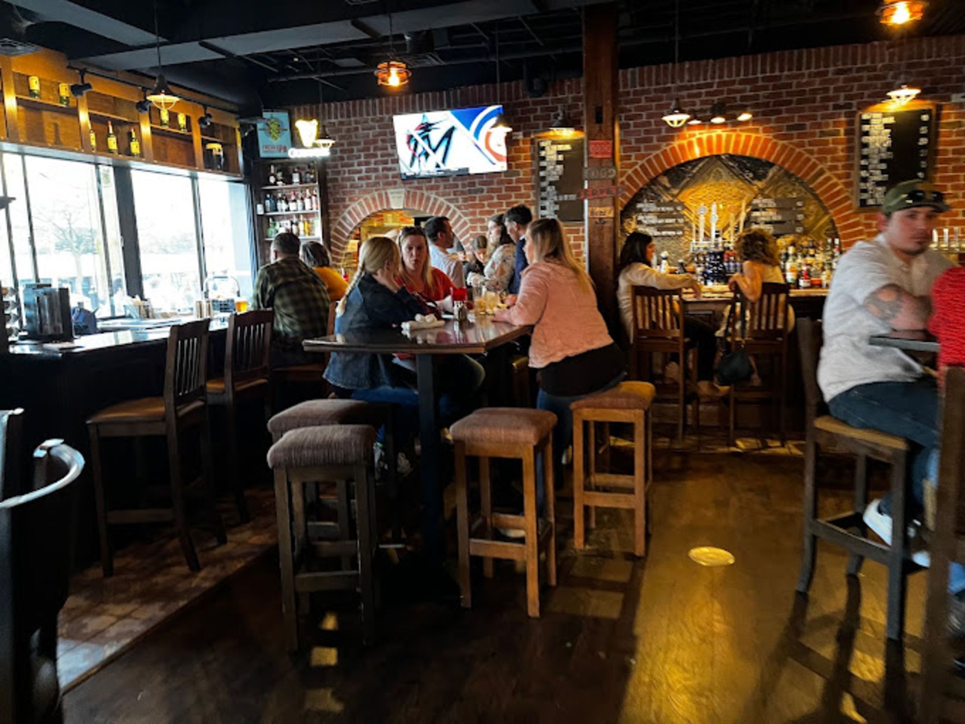 Interior of a crowded bar with brick walls, tables, and people drinking and eating.