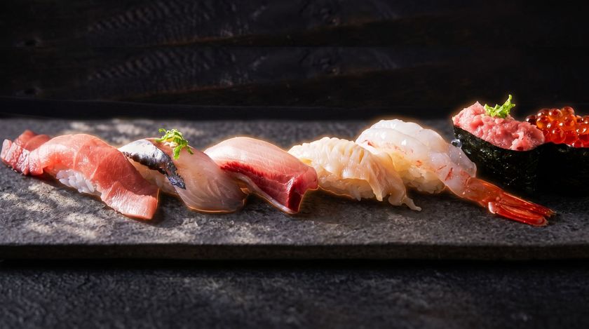 Assorted colorful sushi rolls with salmon, avocado, and sauce on a platter