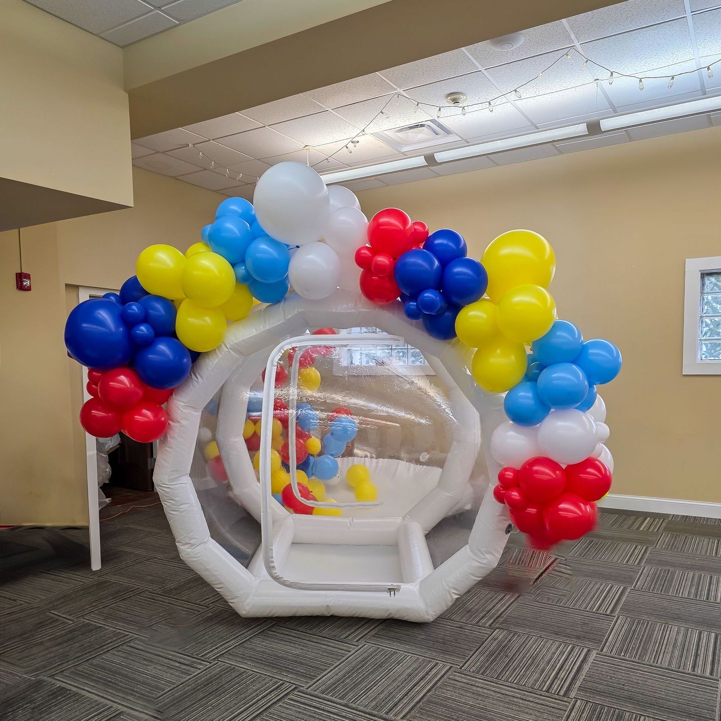 Inflatable balloon bubble house with colorful balloons, indoors.