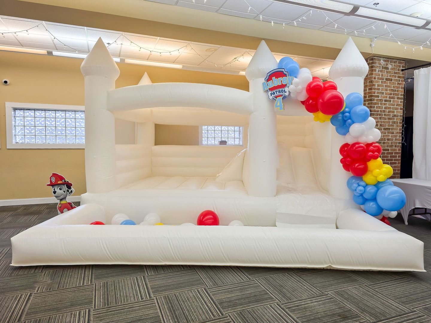 White inflatable bounce  castle with balloon column and ball pit.