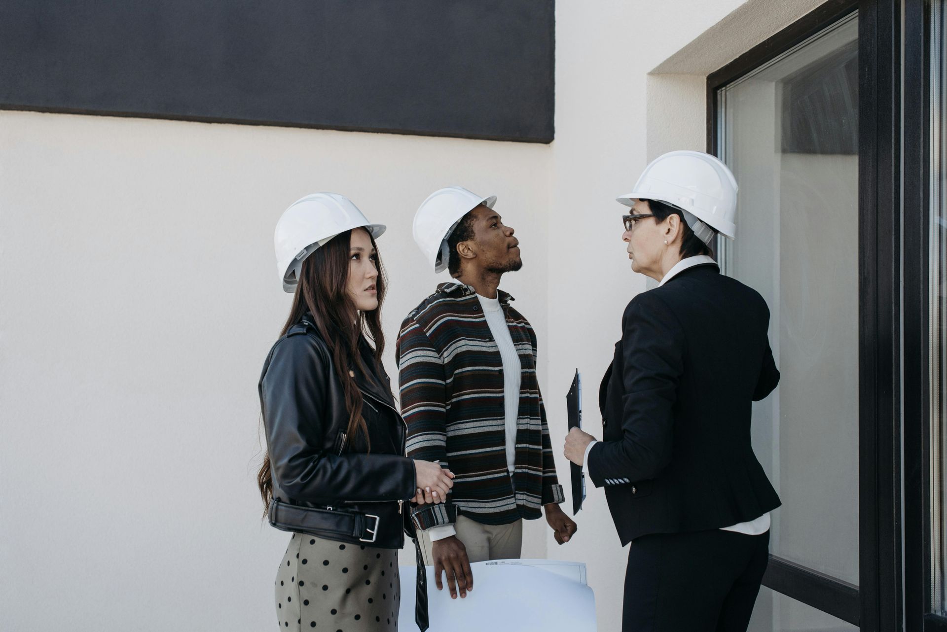 Three coworkers in hard hats discussing plans at a construction site