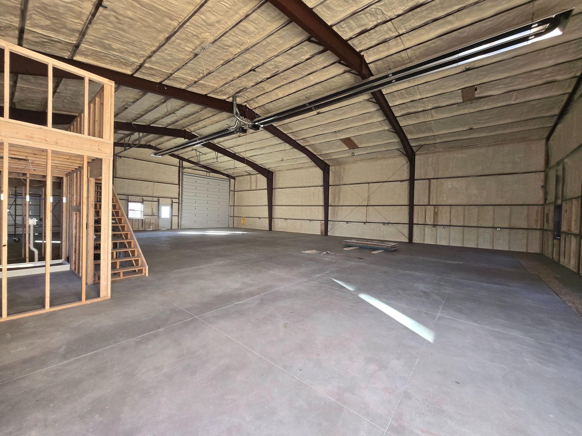 Empty industrial warehouse interior with metal frame walls and concrete floor under construction