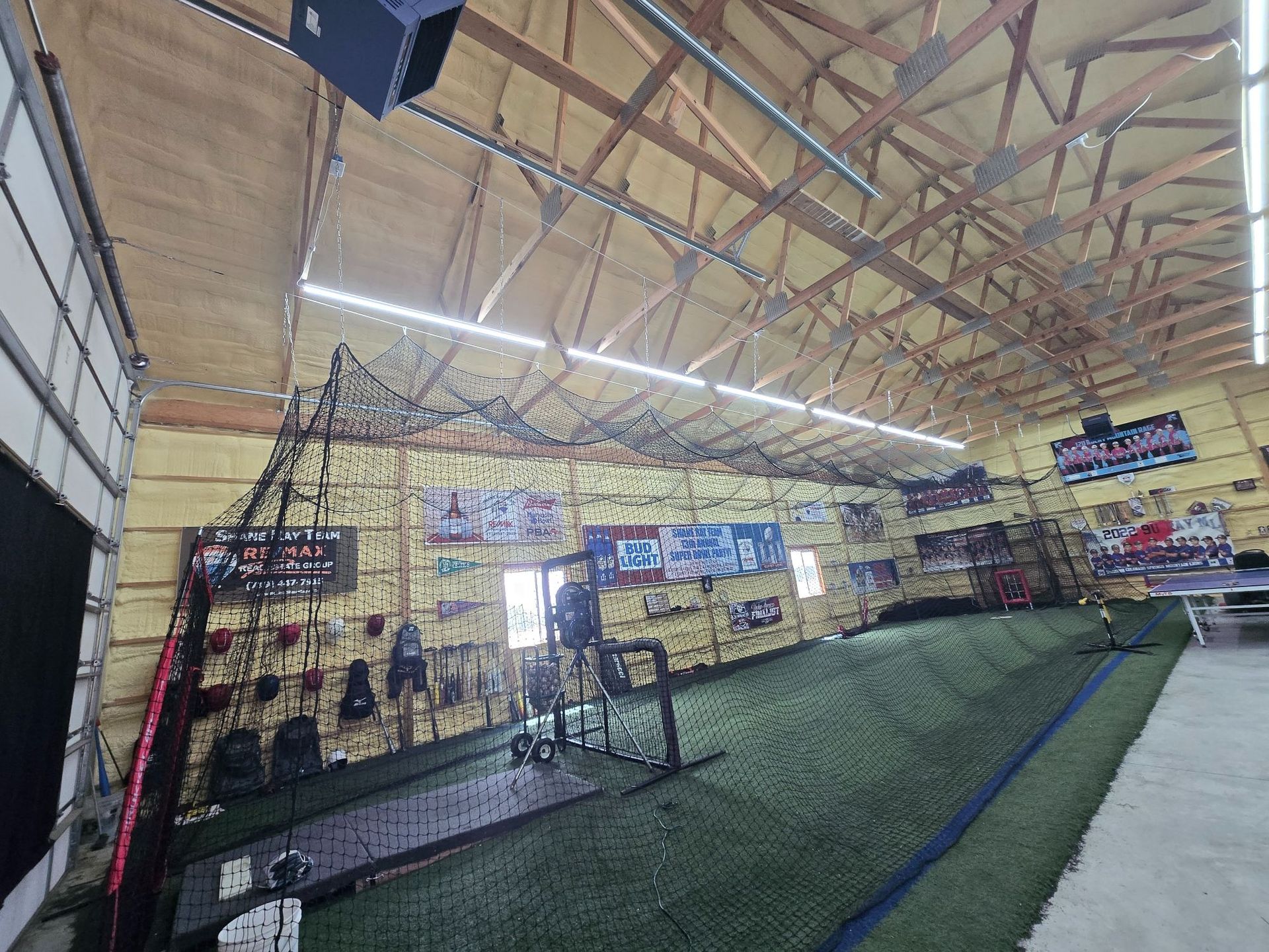 Indoor sports training facility with turf lanes, gym equipment, and a high wooden ceiling