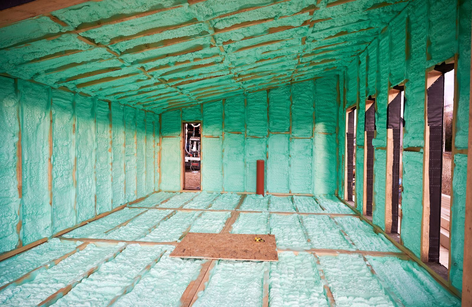 Interior of a building under construction, covered in green spray foam insulation.