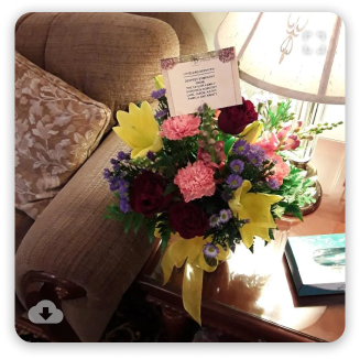 Bouquet of pink, purple, and yellow flowers on a table beside a beige sofa by a window