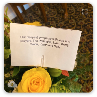 Note with sympathy message displayed among yellow roses and greenery