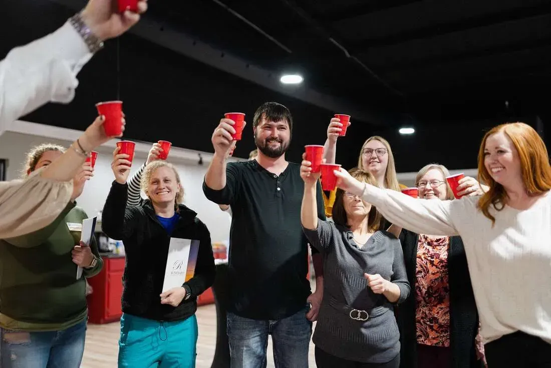 Group of people cheering with red cups in a dim indoor party setting