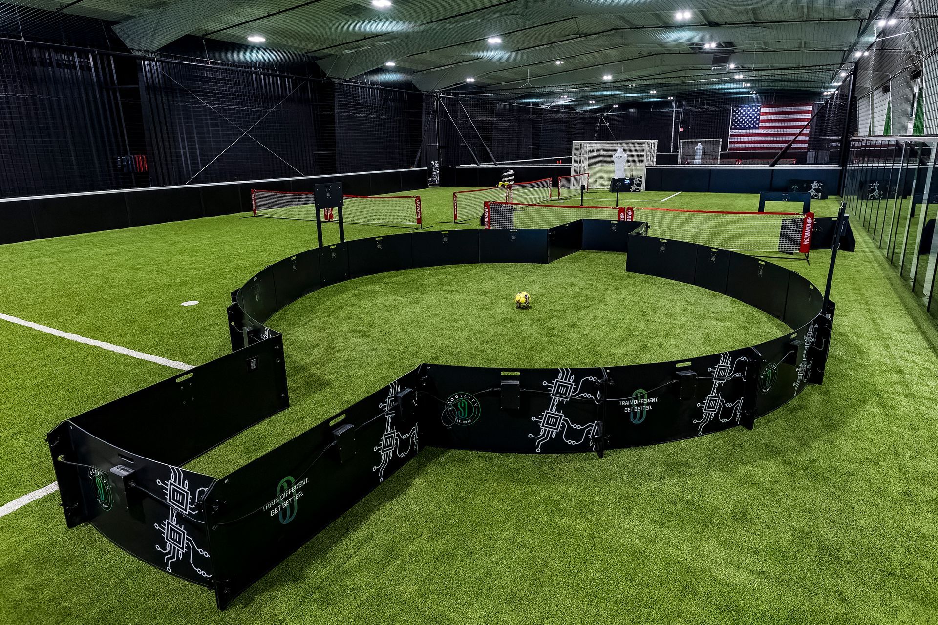 A large indoor soccer field with green and white fences and a goal.