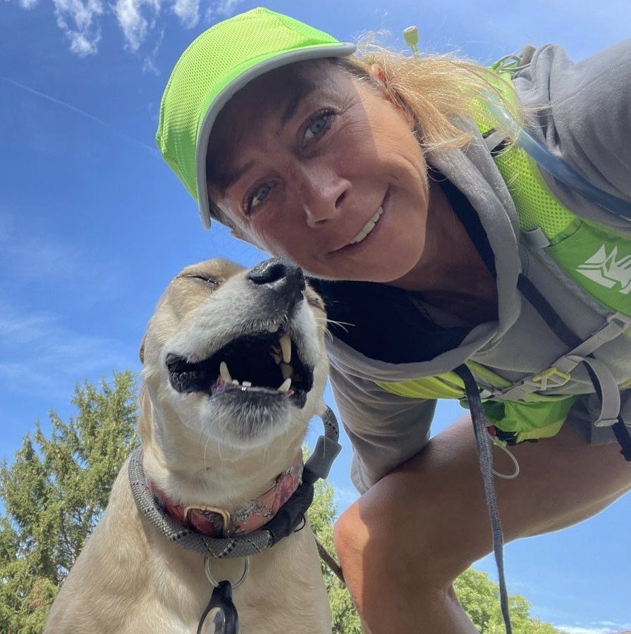 A woman wearing a green hat is posing for a picture with her dog