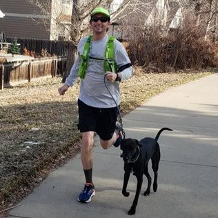 A Denver Dog Jogger is running with a black dog on a leash.
