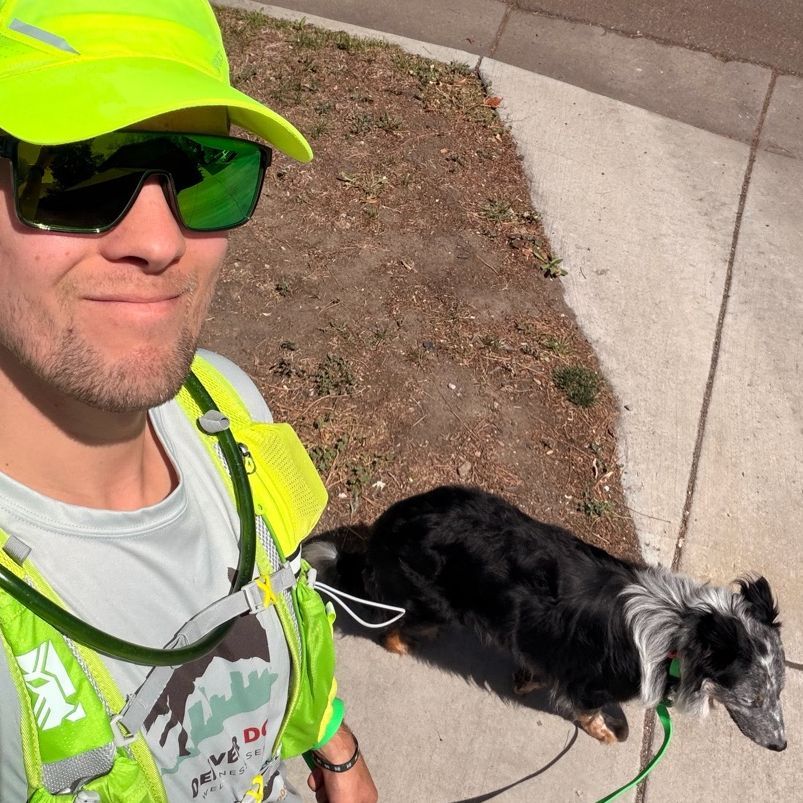Corey N in sunglasses walking a long haired dog.