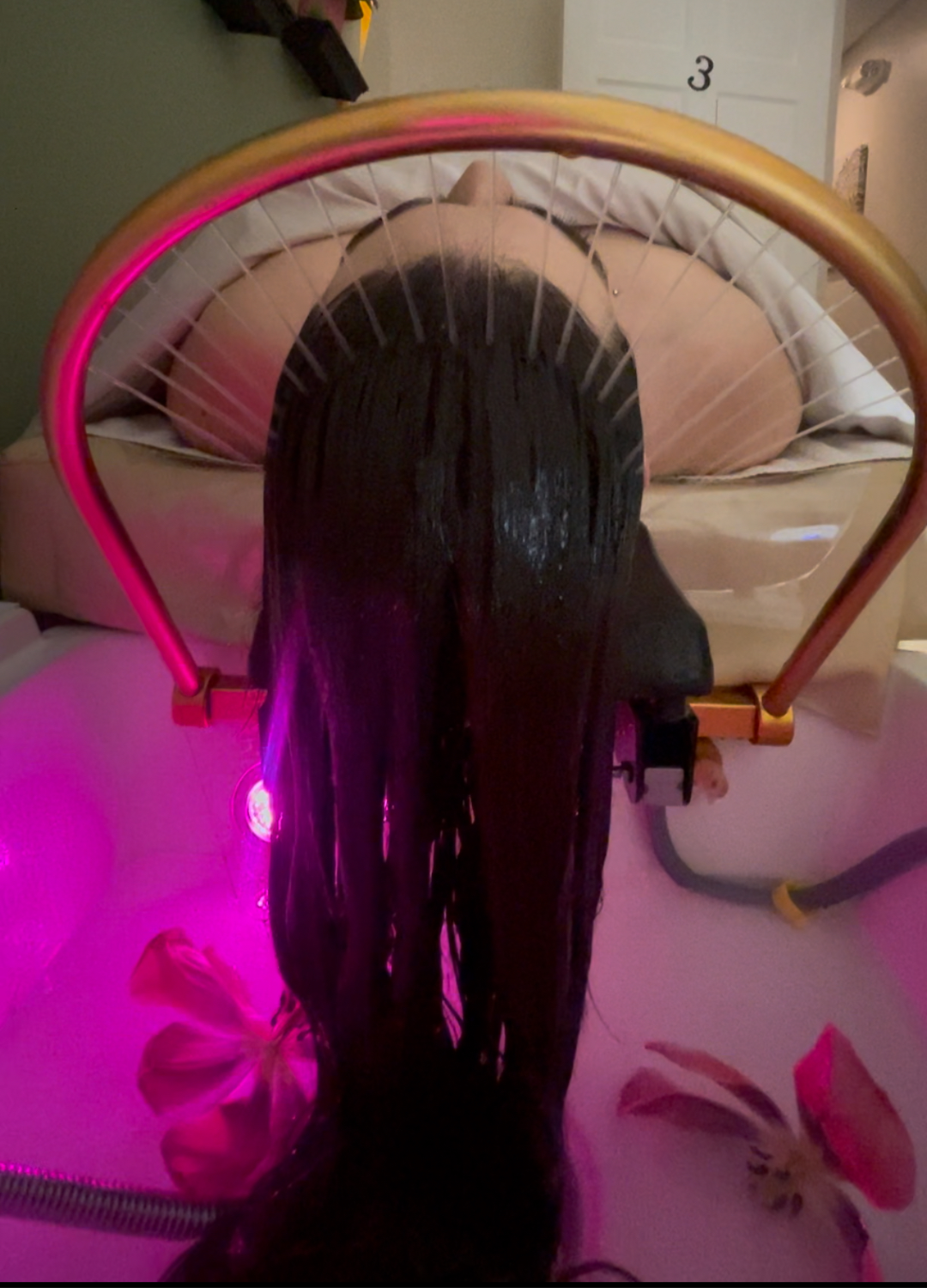 Woman having her hair treated with a pink light device in a salon.
