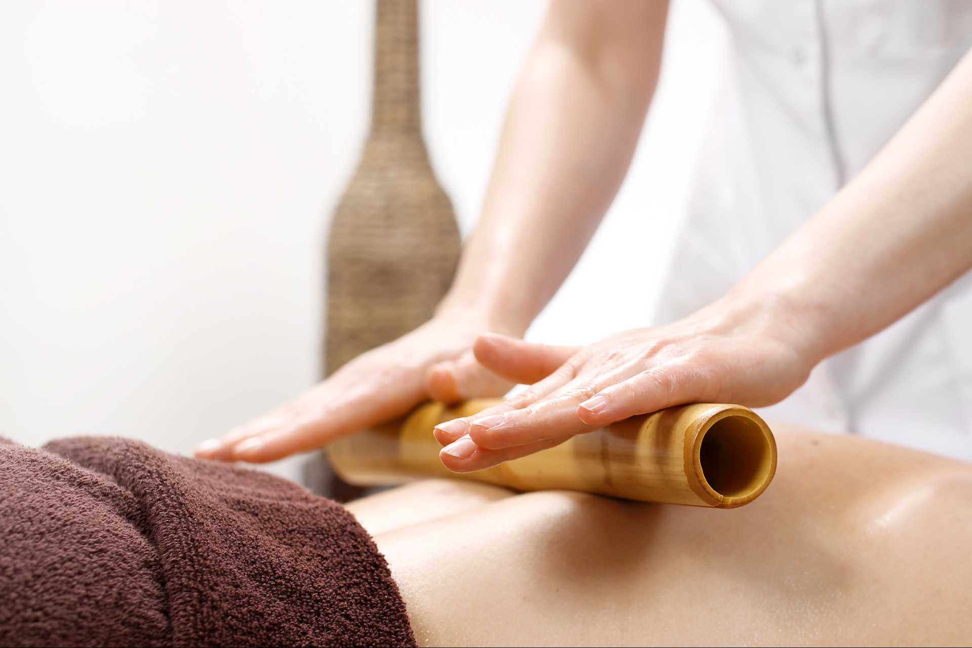Bamboo Massage being given to the back of a TLC Massage client