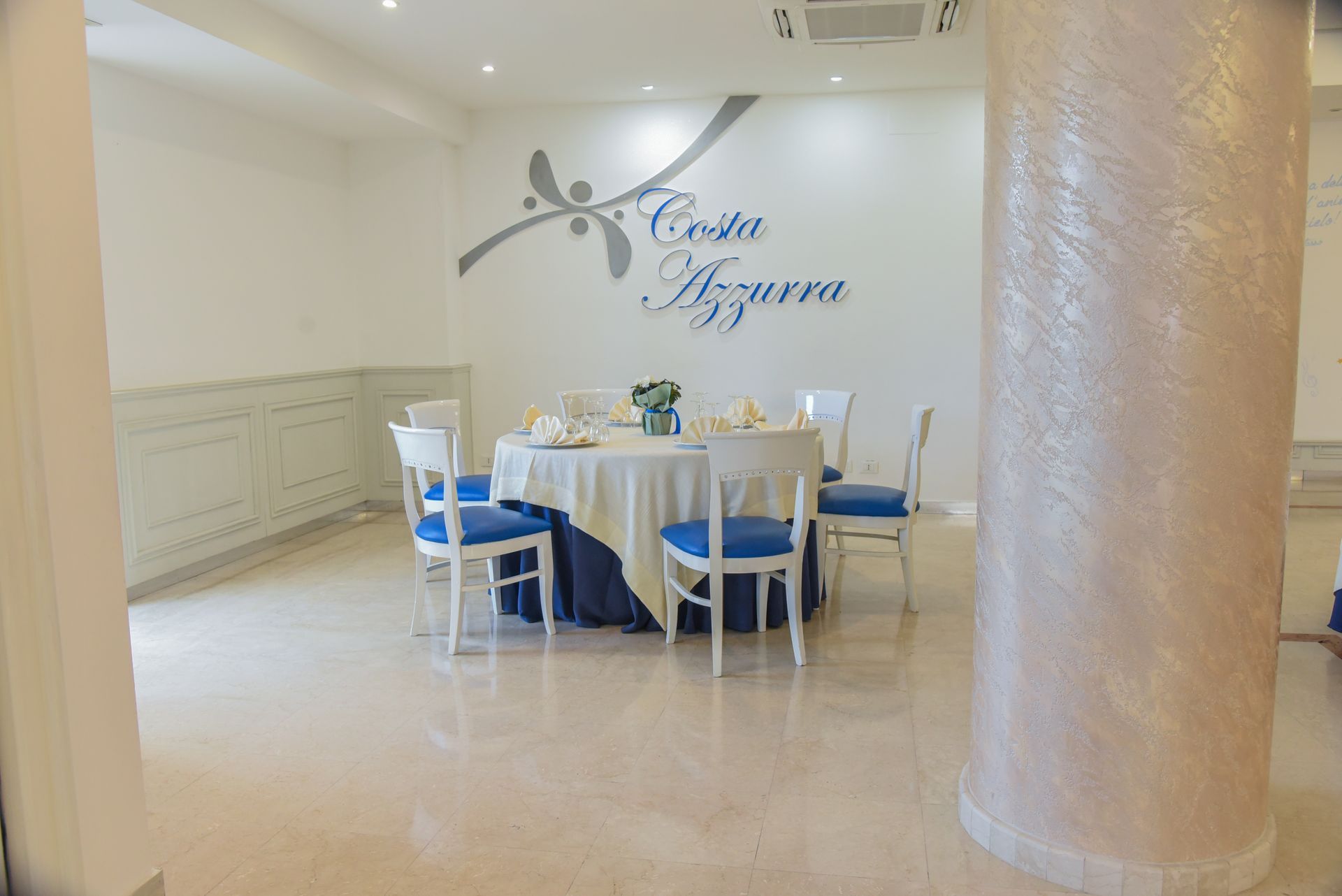 Elegante tavolo da banchetto con decorazioni bianche e blu in una stanza luminosa con una colonna decorativa
