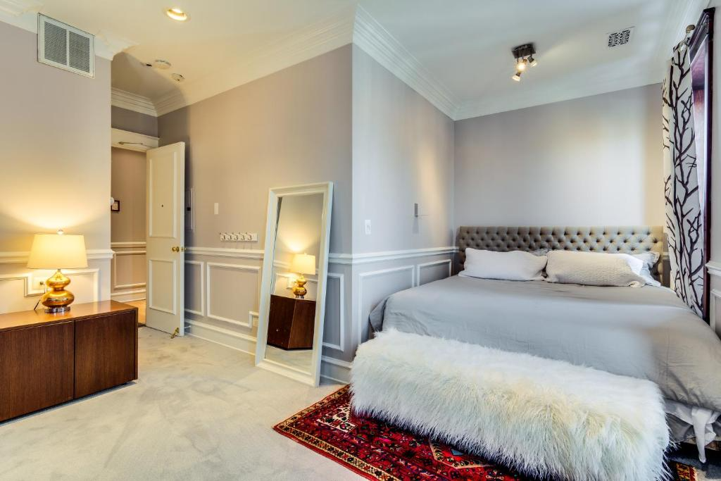Bedroom with gray walls, bed, rug, and full-length mirror. A doorway leads to a hallway.