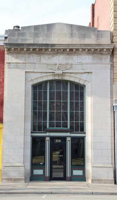 Stone-front building entrance with tall arched glass doors and decorative trim