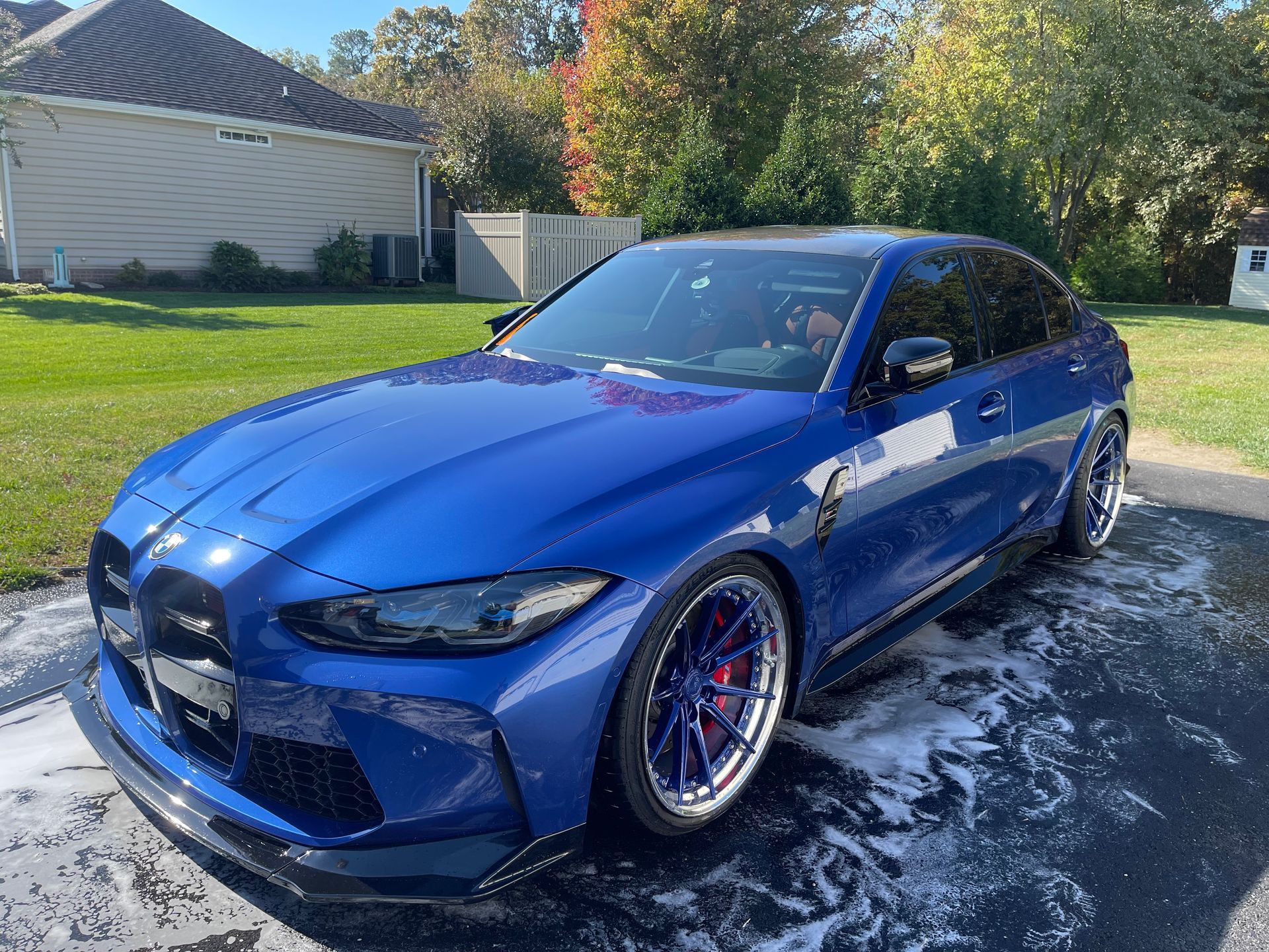 A blue bmw m3 is parked in a driveway next to a house.