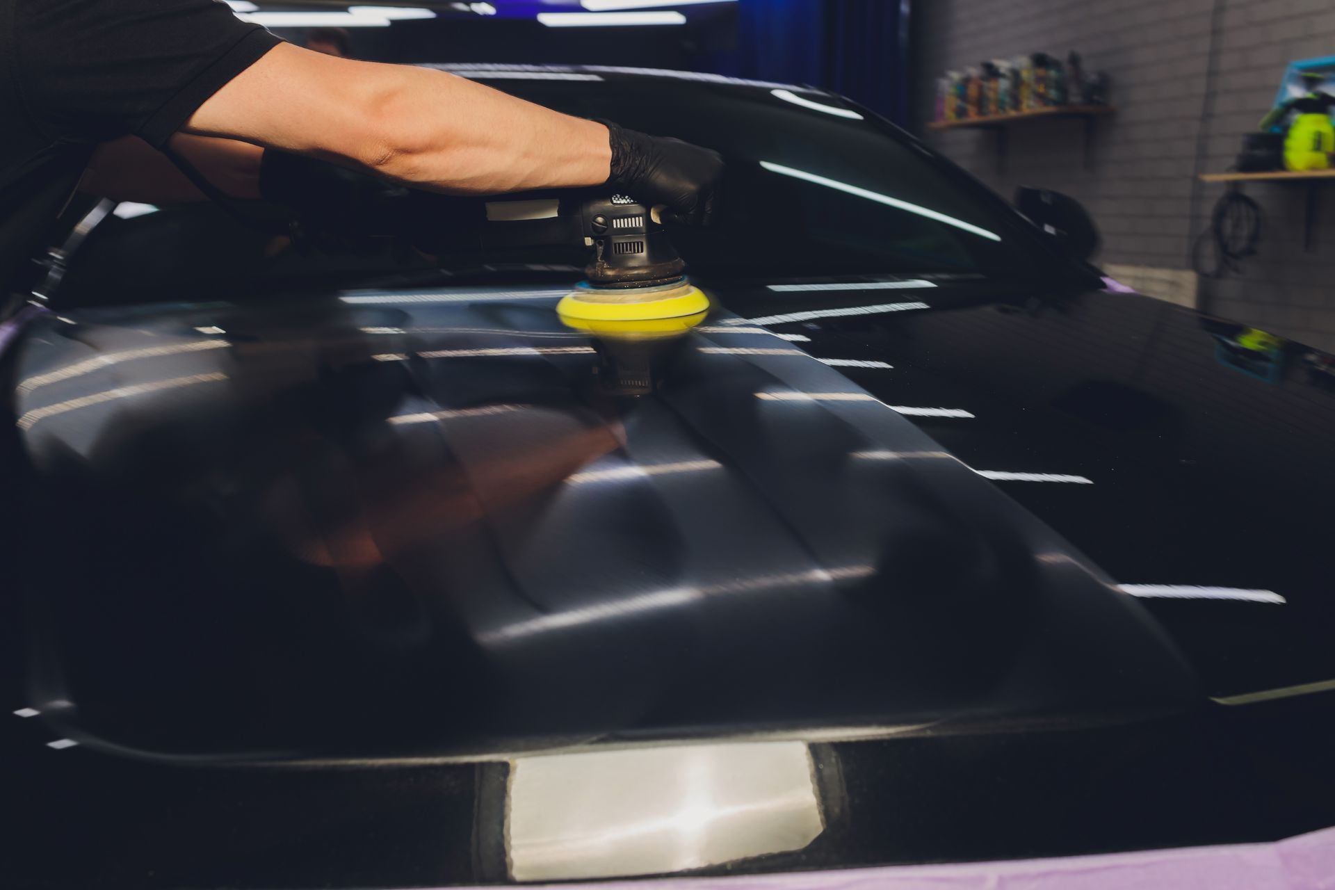 A person is polishing the hood of a car