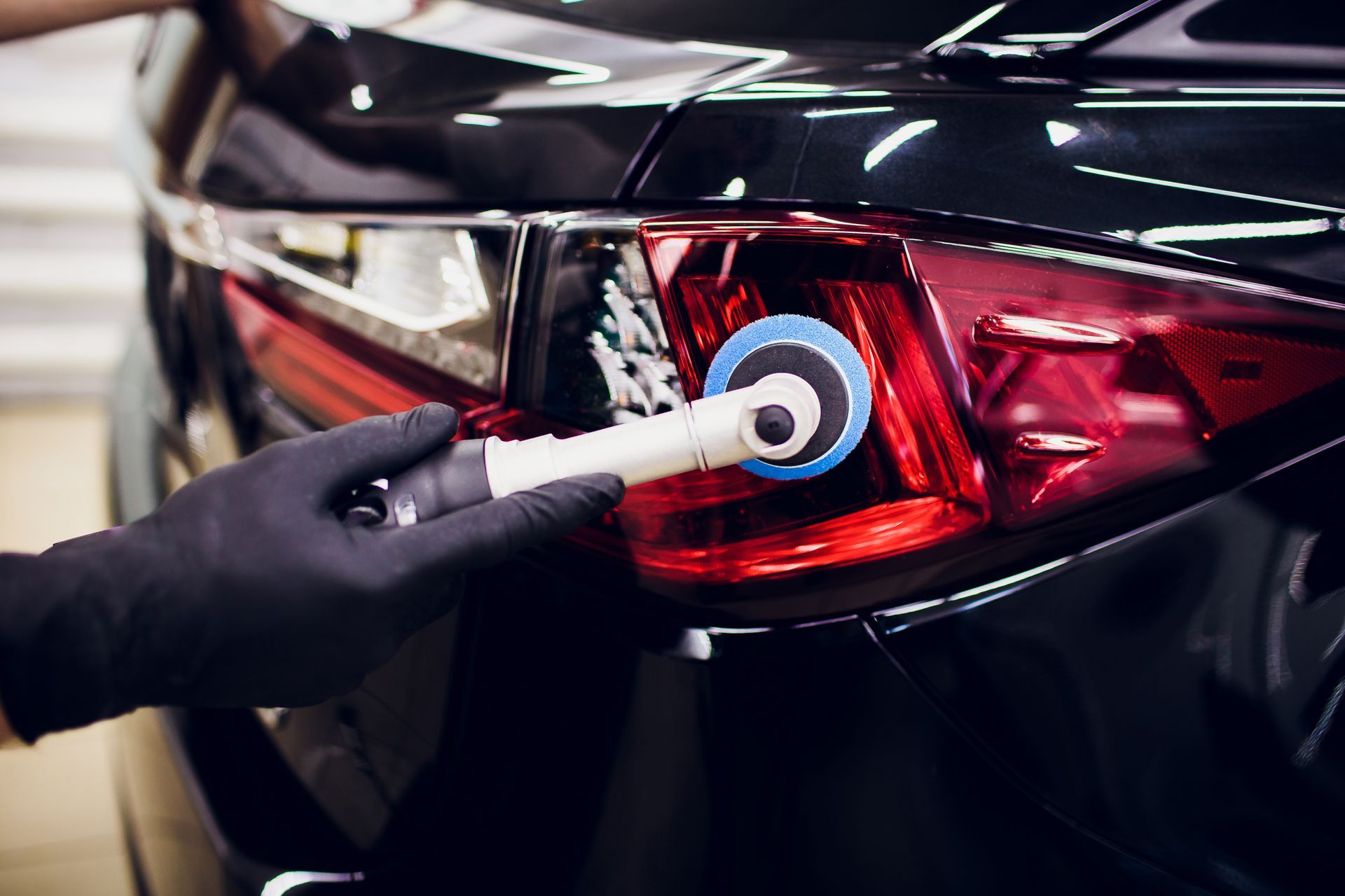 A person is polishing the tail light of a car.