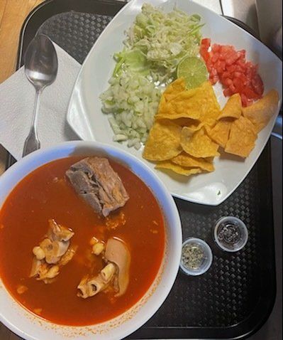 A bowl of soup next to a plate of tortilla chips
