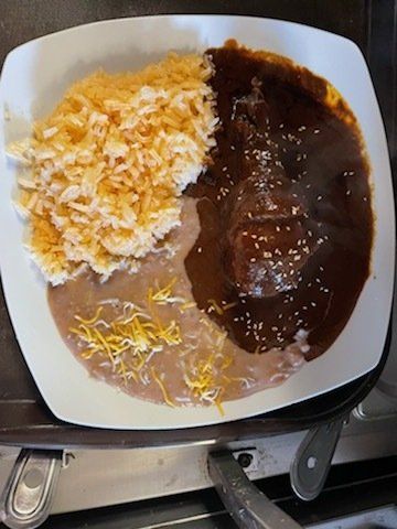 A plate of food with rice beans and sauce on a table.
