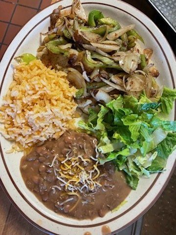 A plate of food with rice , beans , and a salad on a table.