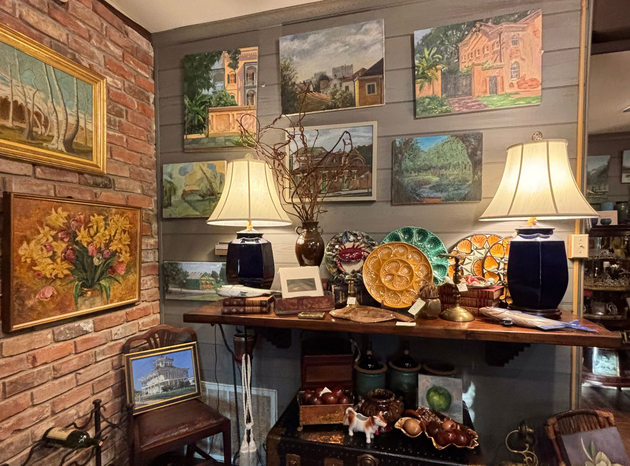 Cozy room with framed landscape paintings, lamps, and decorative pottery on a wooden table