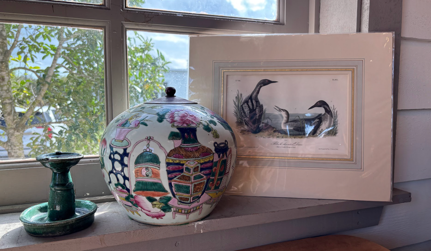 Decorative glass vase, painted plate, and framed horse artwork on a windowsill