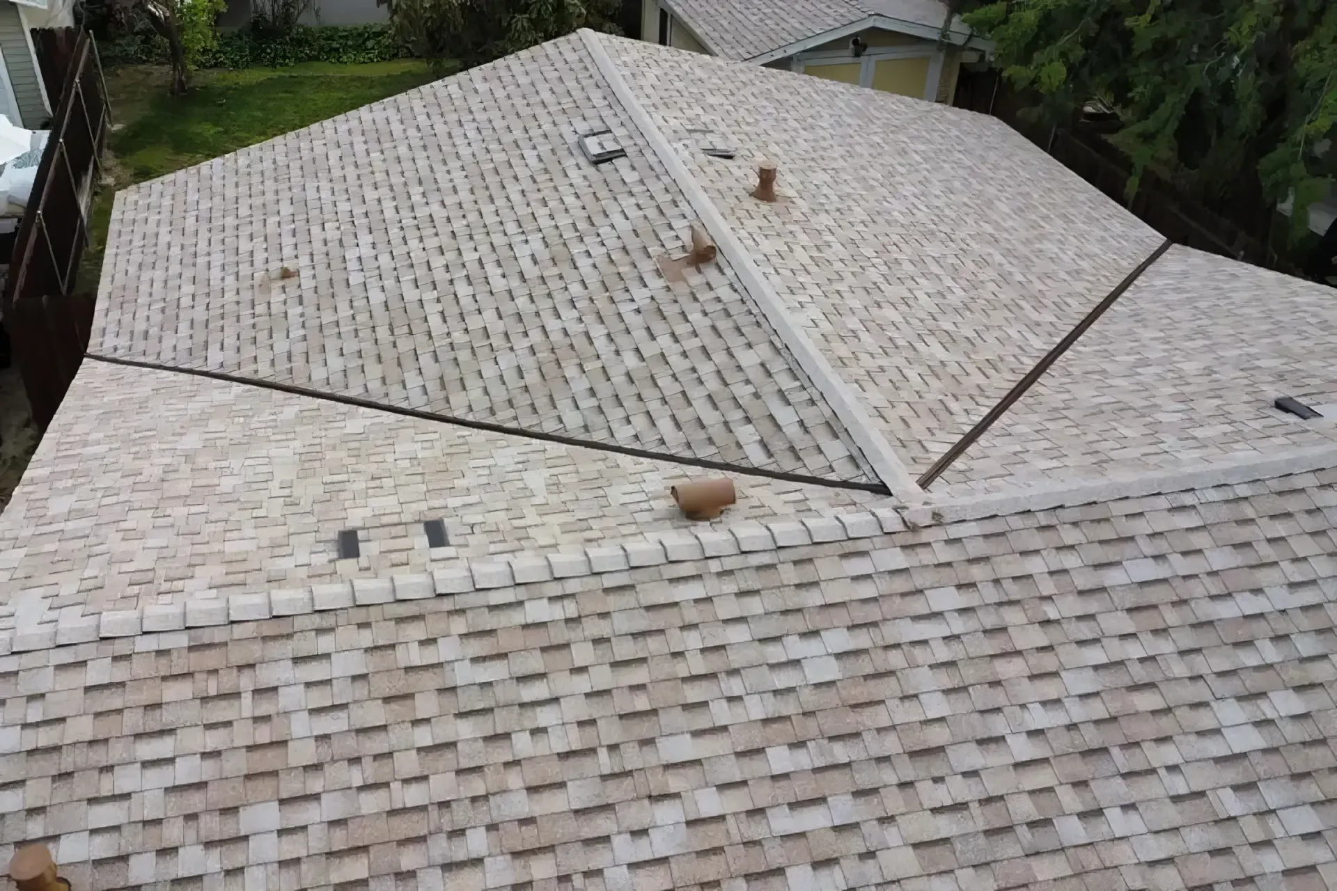 Aerial view of a light-colored tiled roof with multiple sloped sections and small roof vents.