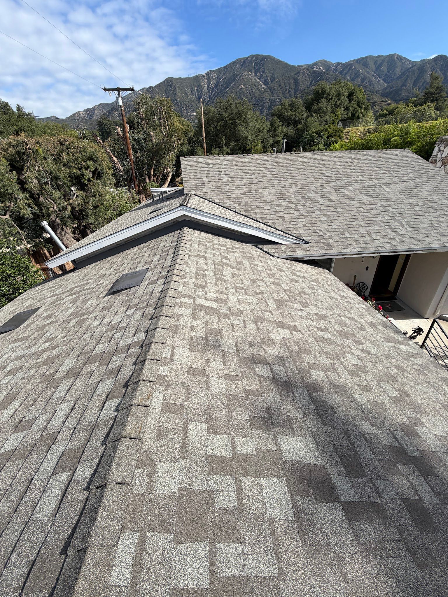 Rooftops with gray shingles in front of mountains under a clear sky.