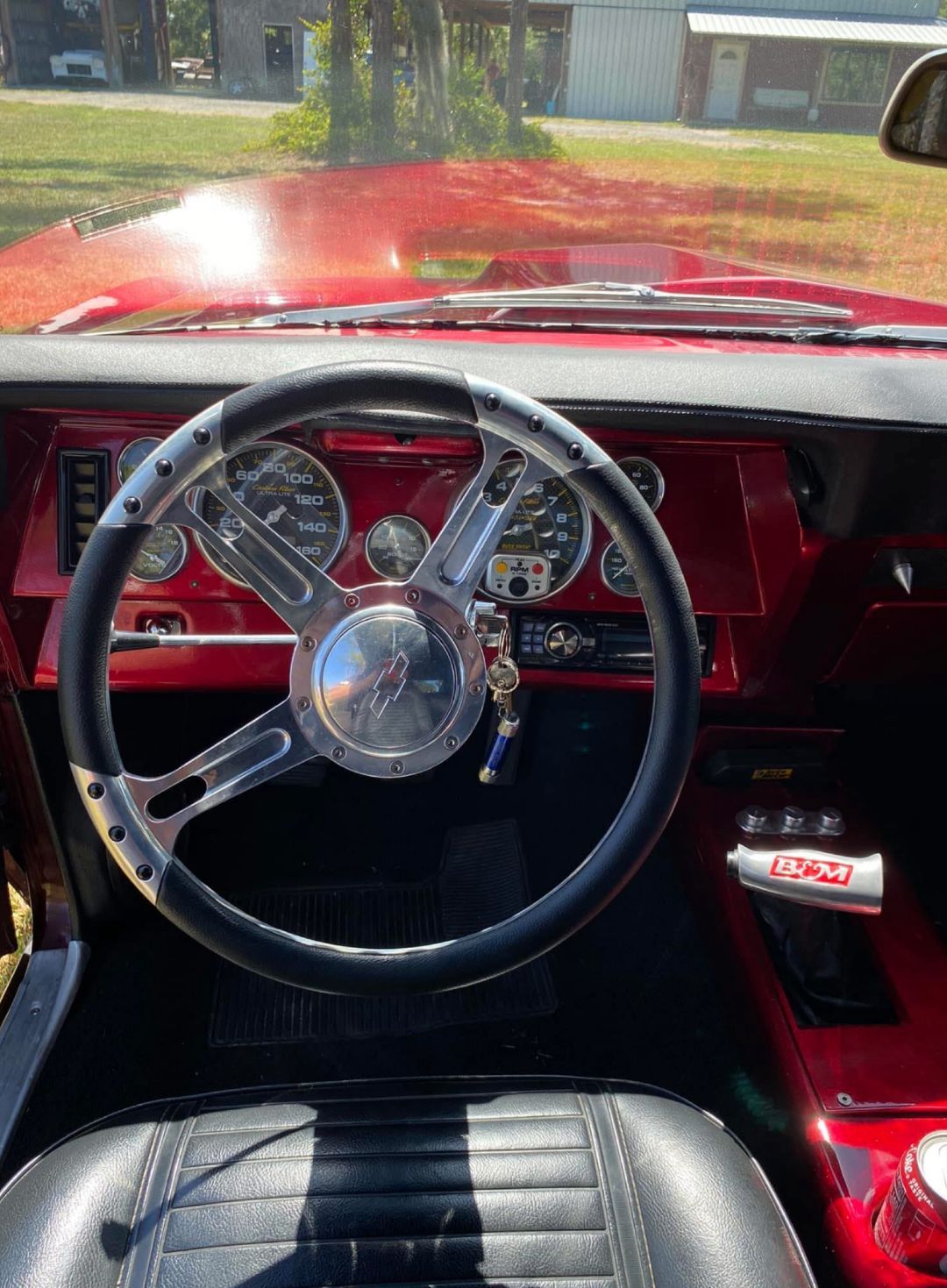 The interior of a red car with a steering wheel and dashboard.