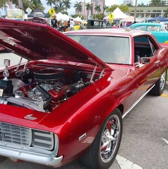 A red car with the hood up is parked in a parking lot