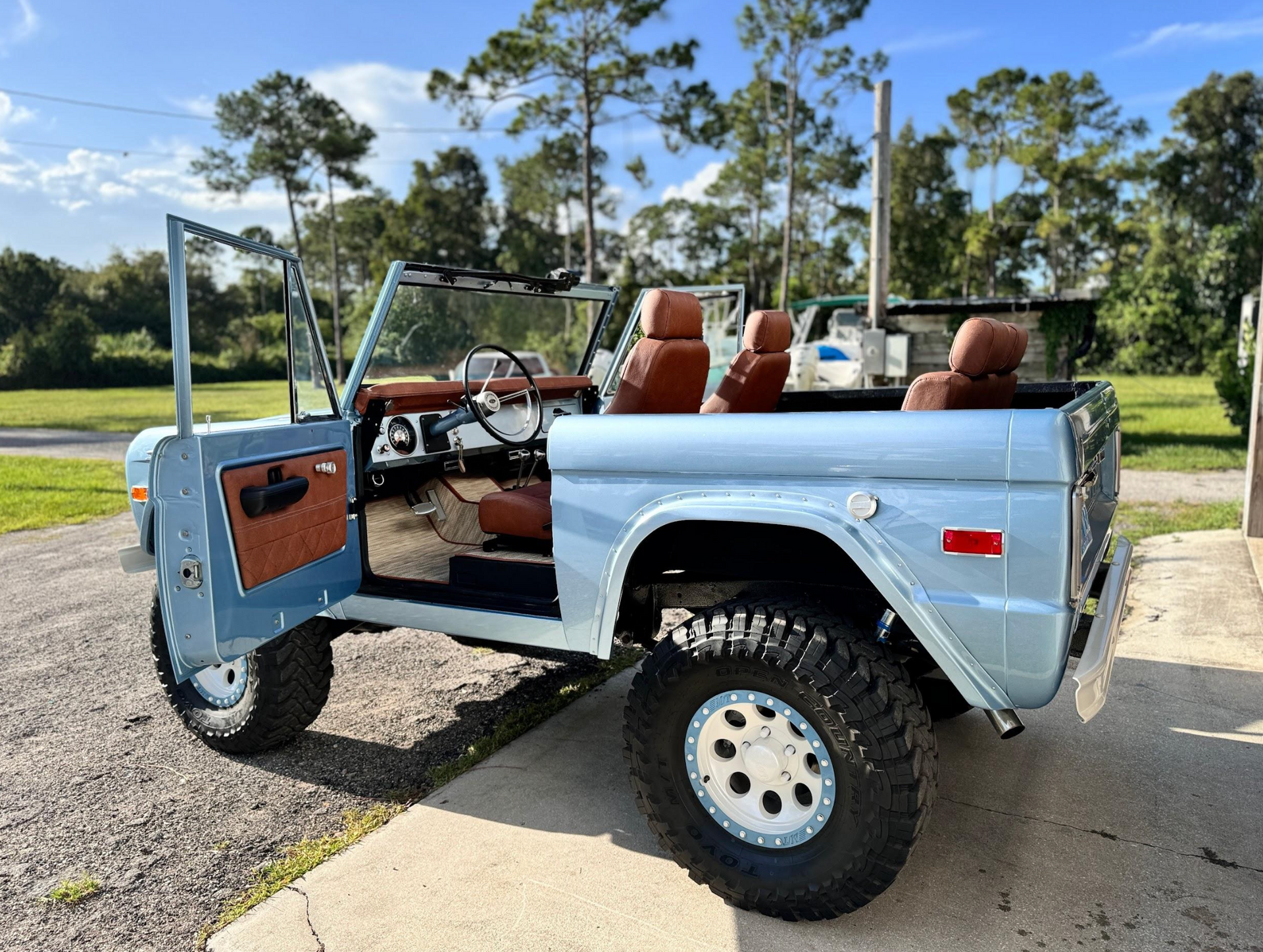 A blue jeep with the doors open is parked on the side of the road.