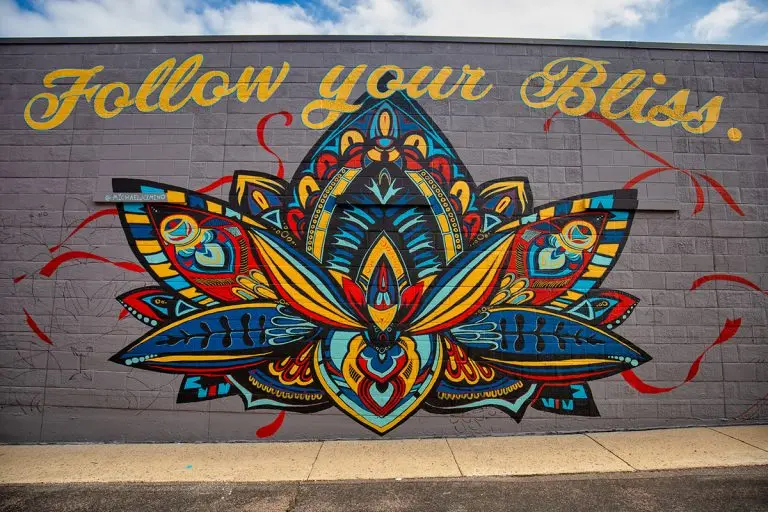 Colorful lotus mural on a brick wall with the words “Follow your Bliss” painted above.
