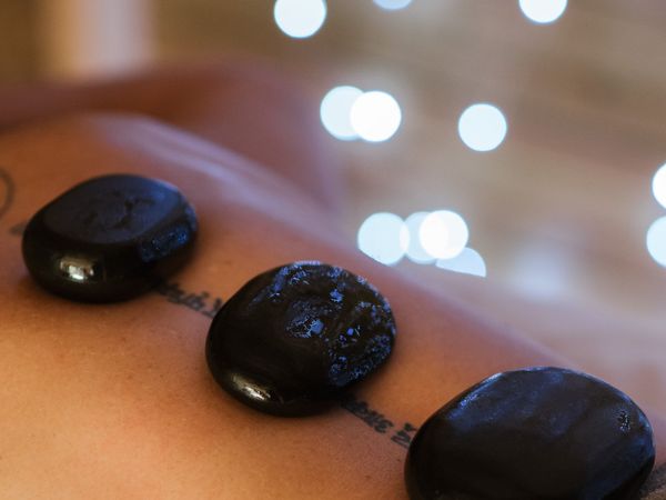 Black hot stones on a bare back with soft spa lights in the background