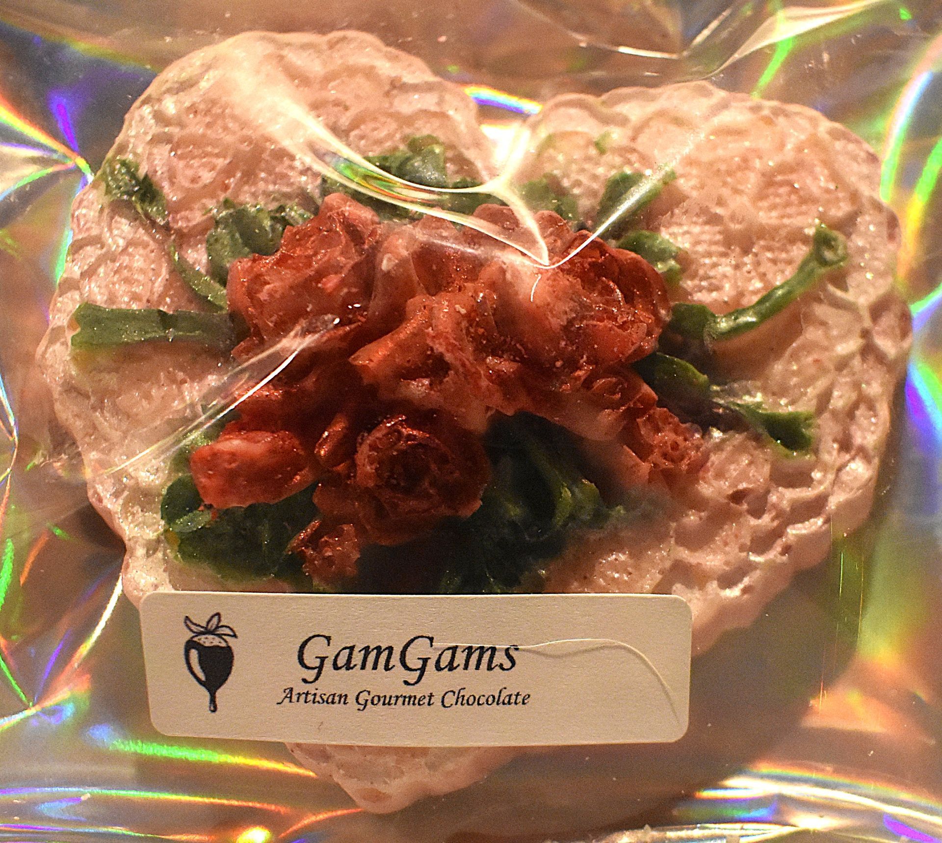 Heart-shaped artisan gourmet chocolate treat from GamGams, topped with red and green details, in clear packaging.
