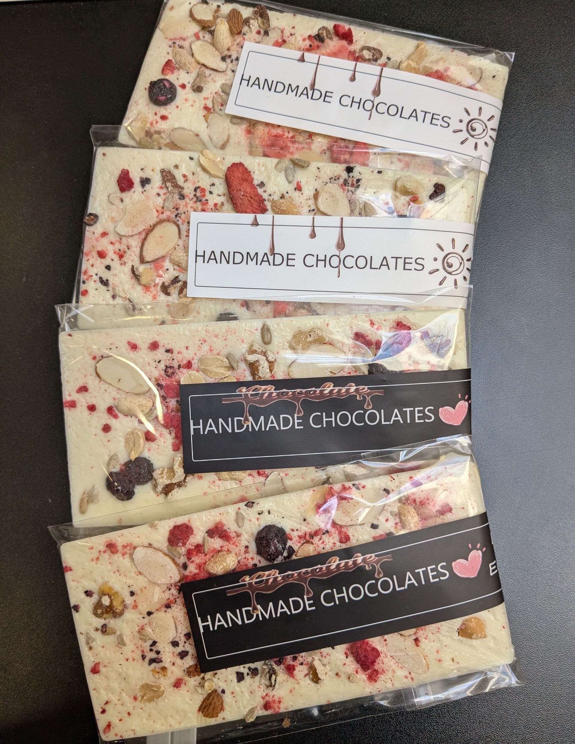Assorted handmade GamGams chocolate bars in cream and dark wrappers on a dark surface