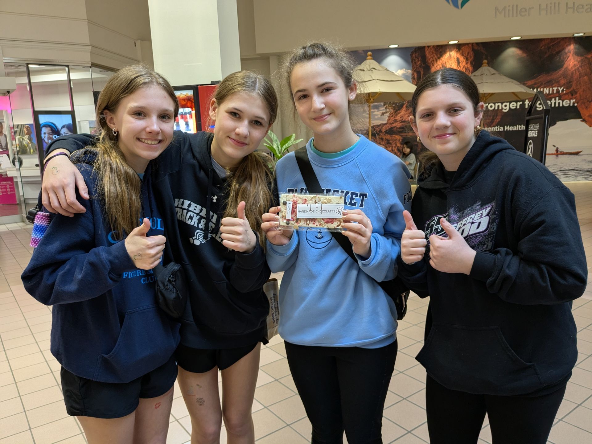 Four friends in Duluth Mall, holding a GamGams Chcolate Bar they just purchased. Giving thumbs-up.