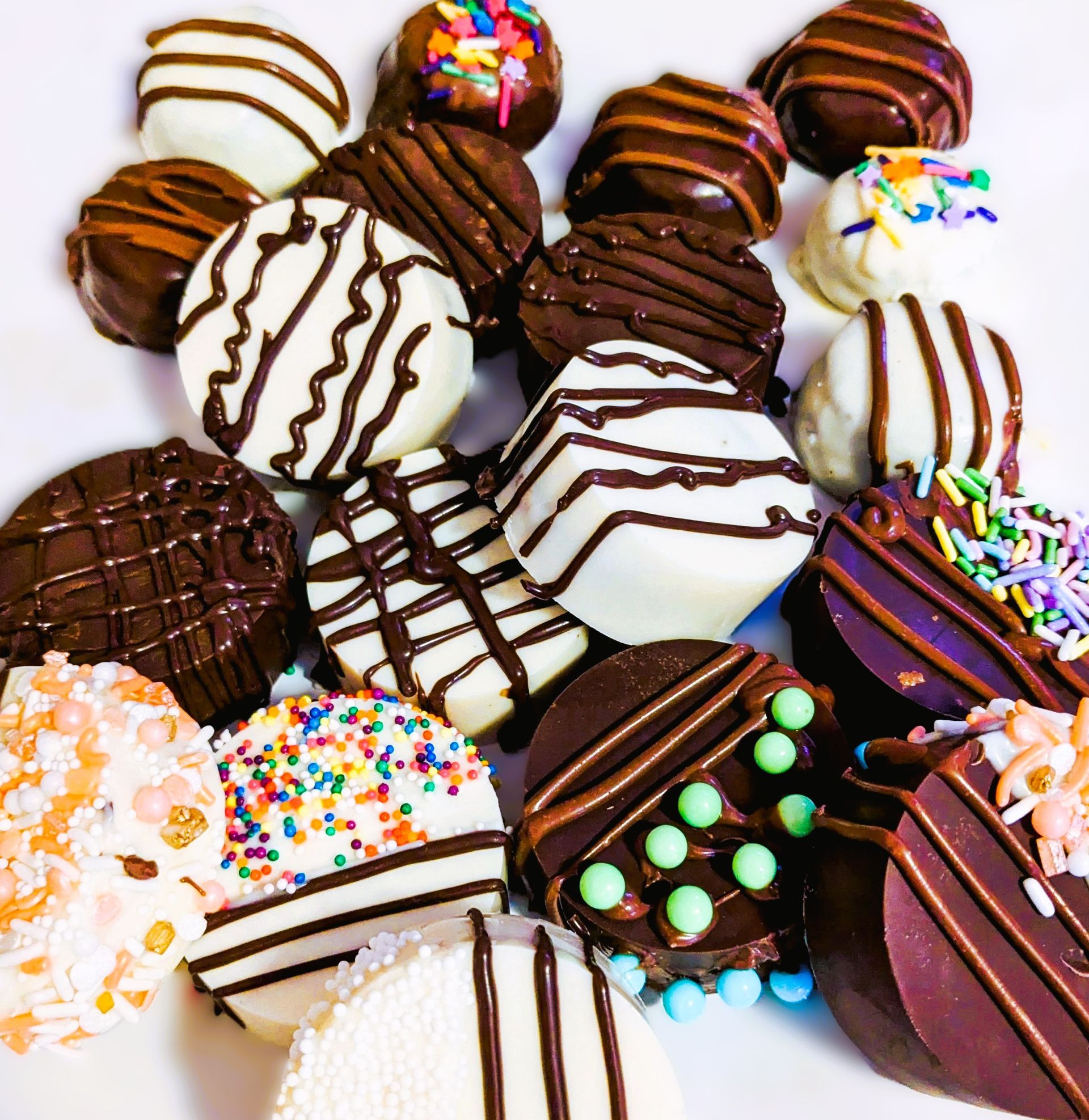 Assorted Oreo Cookie dunks. With chocolate, white, and colorful  chocolate, topped with sprinkles and drizzles on a tray