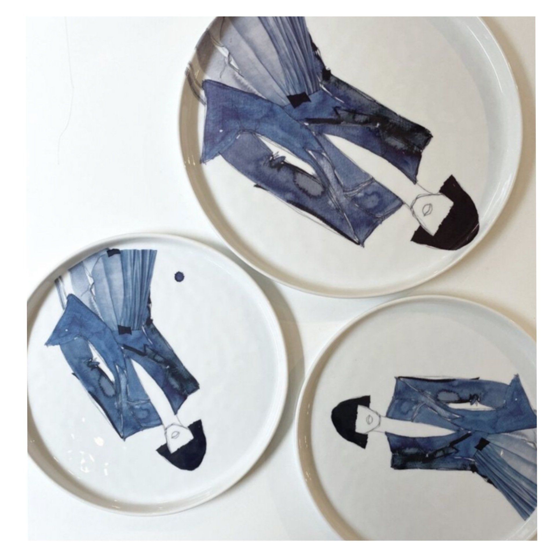 Three white plates with watercolor illustrations of figures in blue suits.