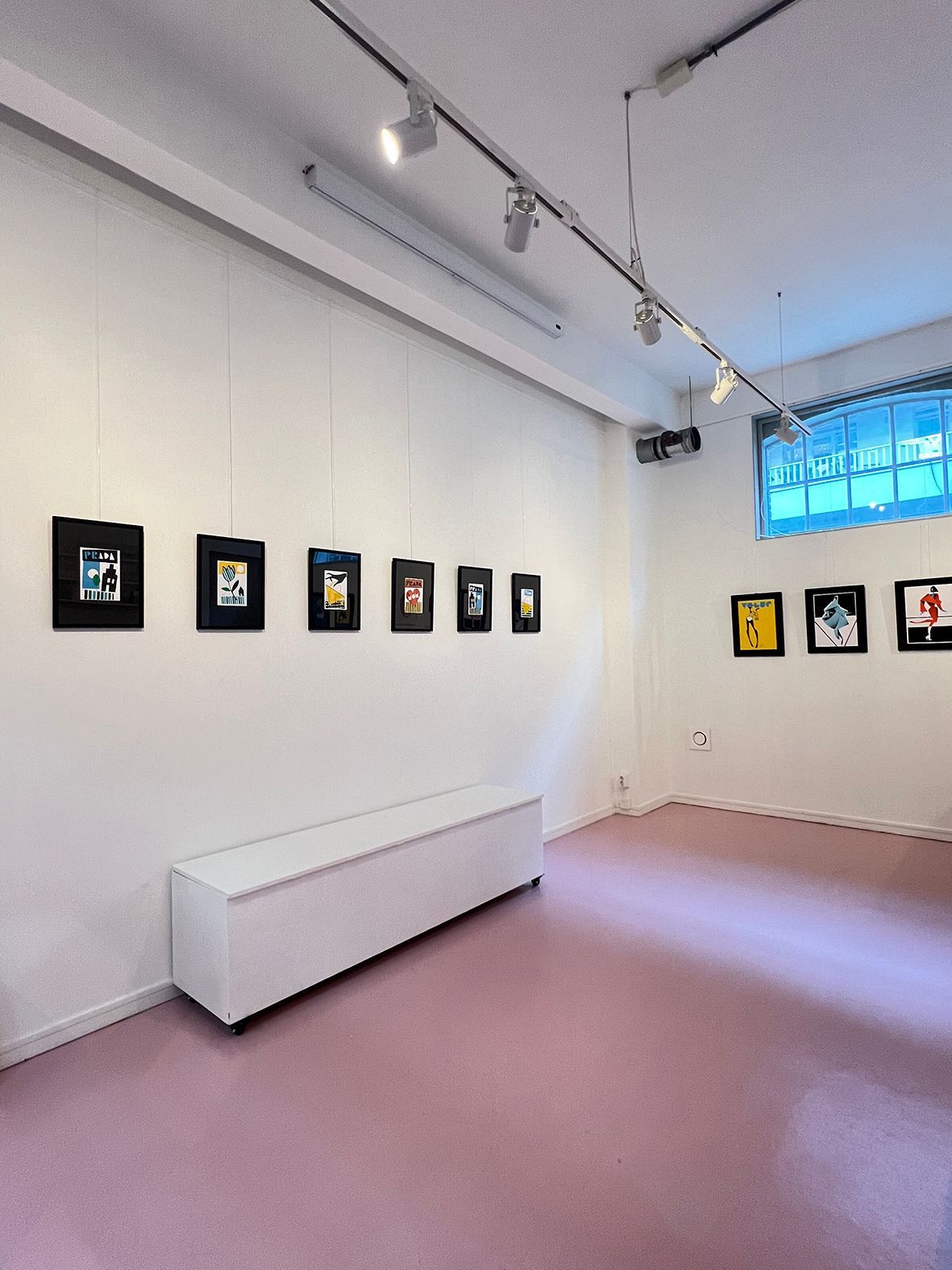 Art gallery with framed artwork hanging on white walls, pink floor, and a white bench.Rental Space Venue at De Hallen Amsterdam
