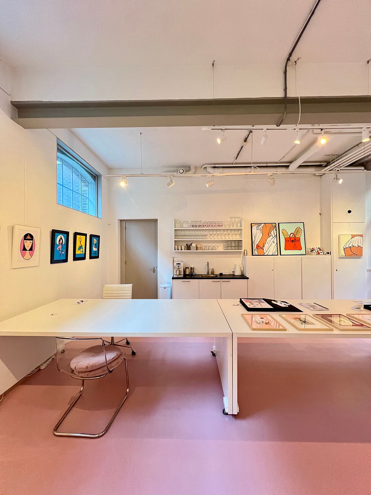 Art gallery interior with a white table, pink floor, and artwork on the walls.Rental Space Venue at De Hallen Amsterdam