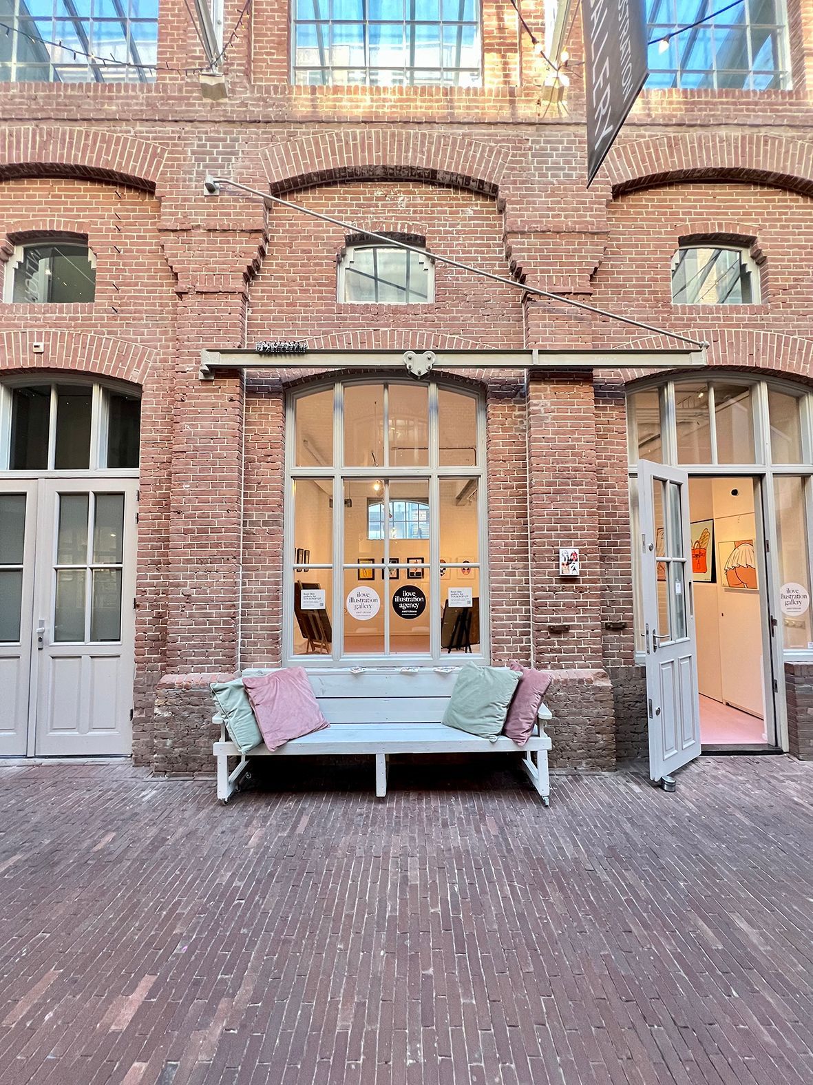 Brick building exterior with bench and open doors; courtyard setting. Rental Space Venue at De Hallen Amsterdam