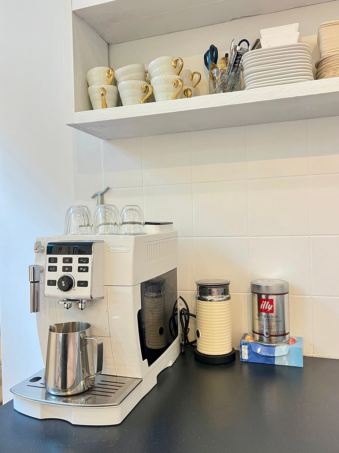 White espresso machine with stainless steel pitcher, beside a milk frother and coffee grinder.Rental Space Venue at De Hallen Amsterdam