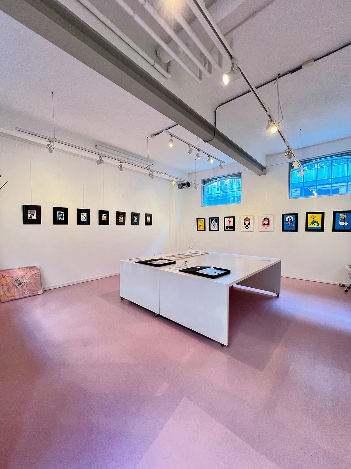 Art gallery interior with pink floor, white walls, and framed artwork. Bright overhead lighting.Rental Space Venue at De Hallen Amsterdam