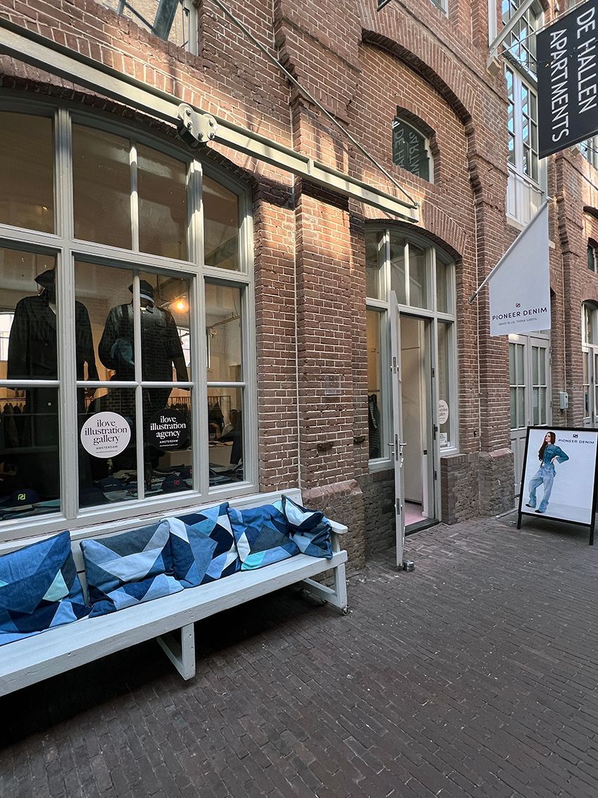 Storefront with brick exterior, large windows, bench with blue denim pillows. Rental Space Venue at De Hallen Amsterdam