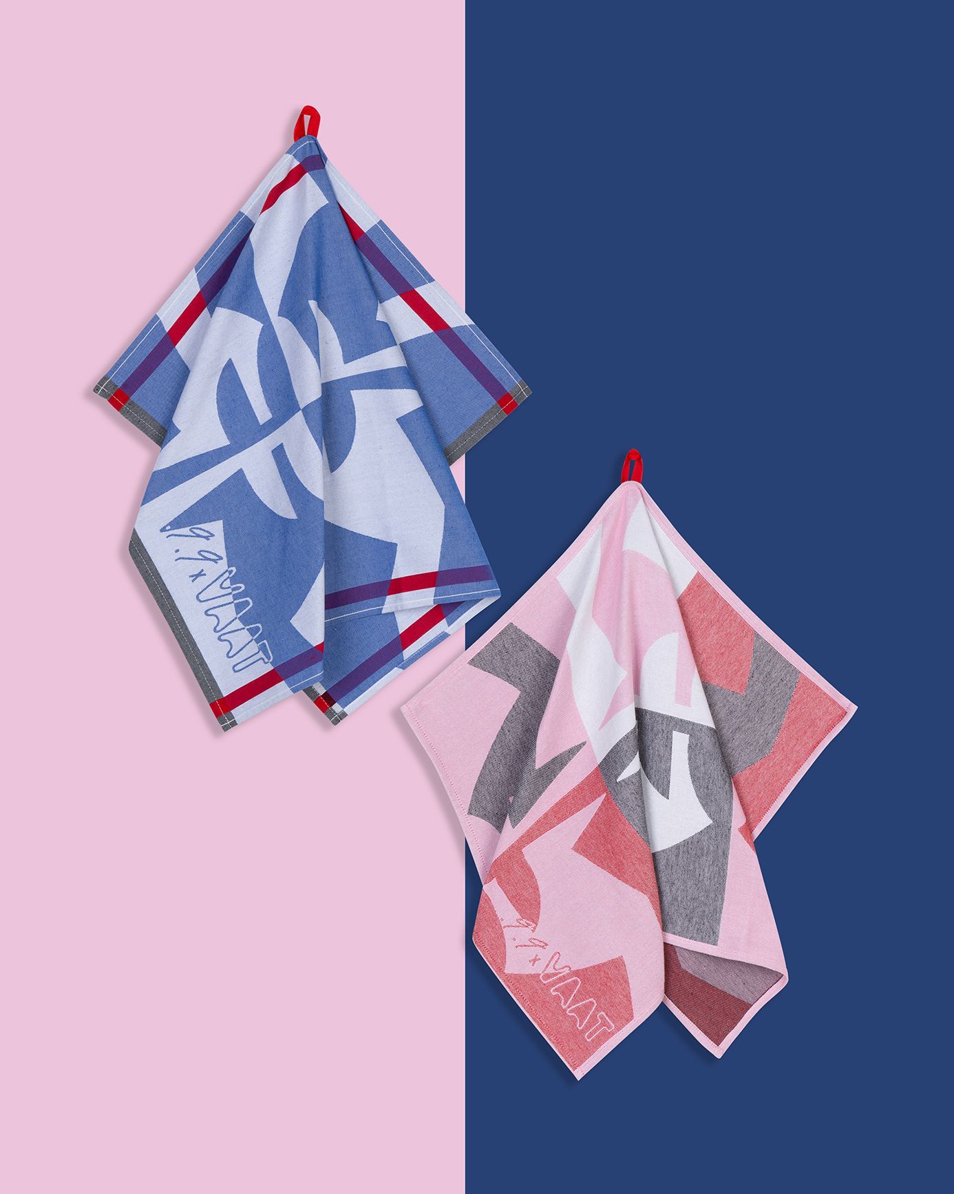 Two patterned hand towels hanging; one blue and white, one pink and gray, both on red hooks.